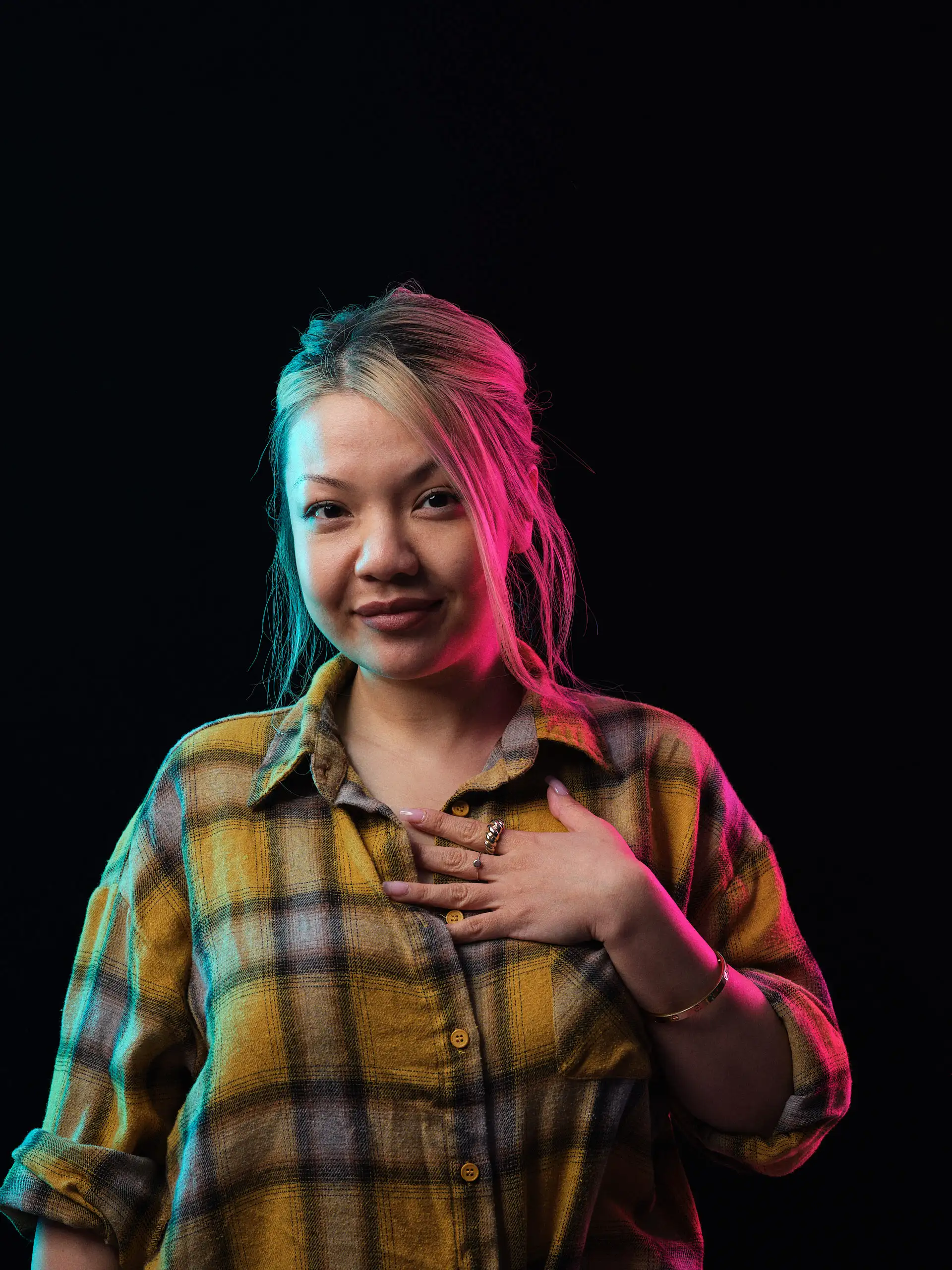 High-contrast studio portrait in yellow plaid featuring magenta and cyan lighting accents.