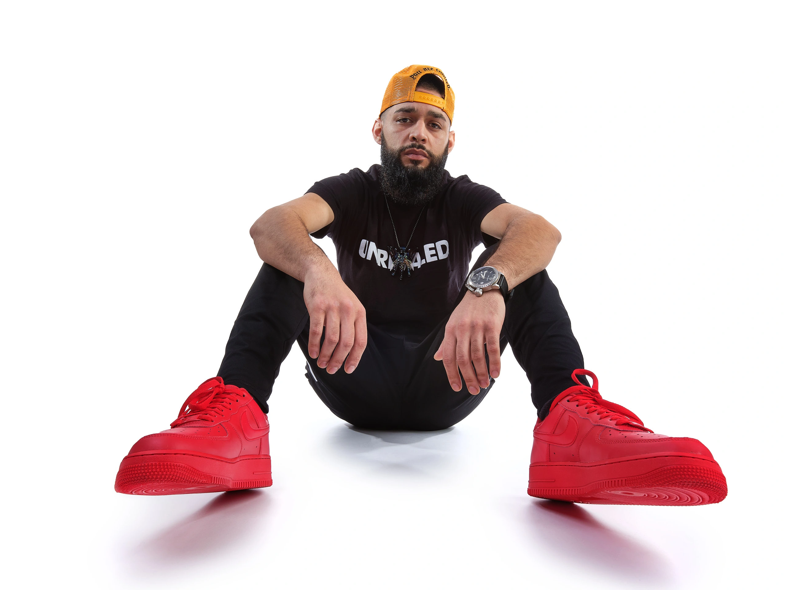 High-key studio commercial portrait by San Francisco photographer; featuring a man in red sneakers and streetwear on a seamless white background, captured with GFX wide-angle and a four-light Broncolor setup.
